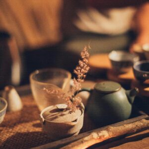 Warm and inviting traditional tea setup with candlelit ambiance, highlighting ceramic tea cups and teapot.